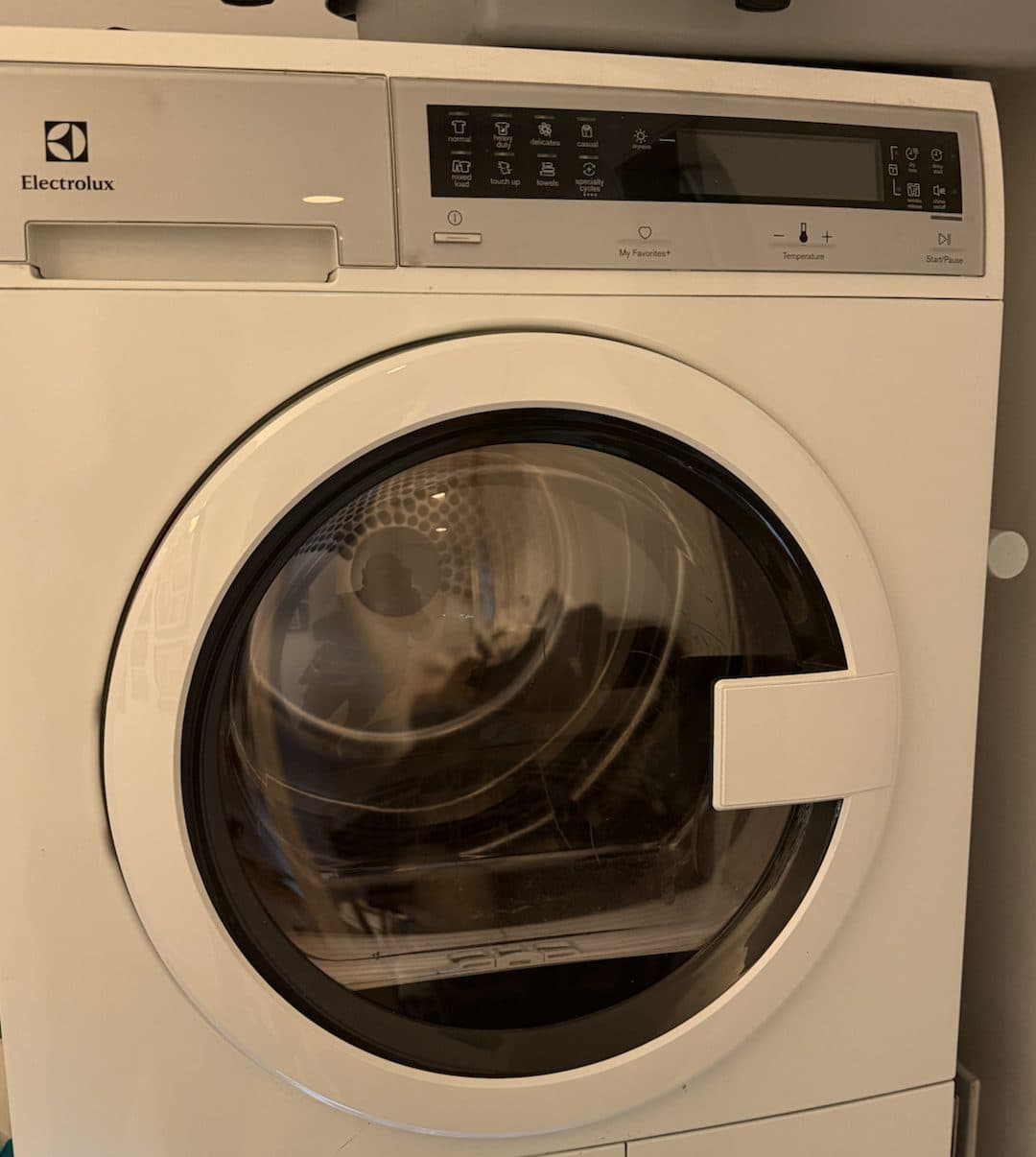 A white Electrolux compact ventless dryer with a round front door and a control panel across the top
