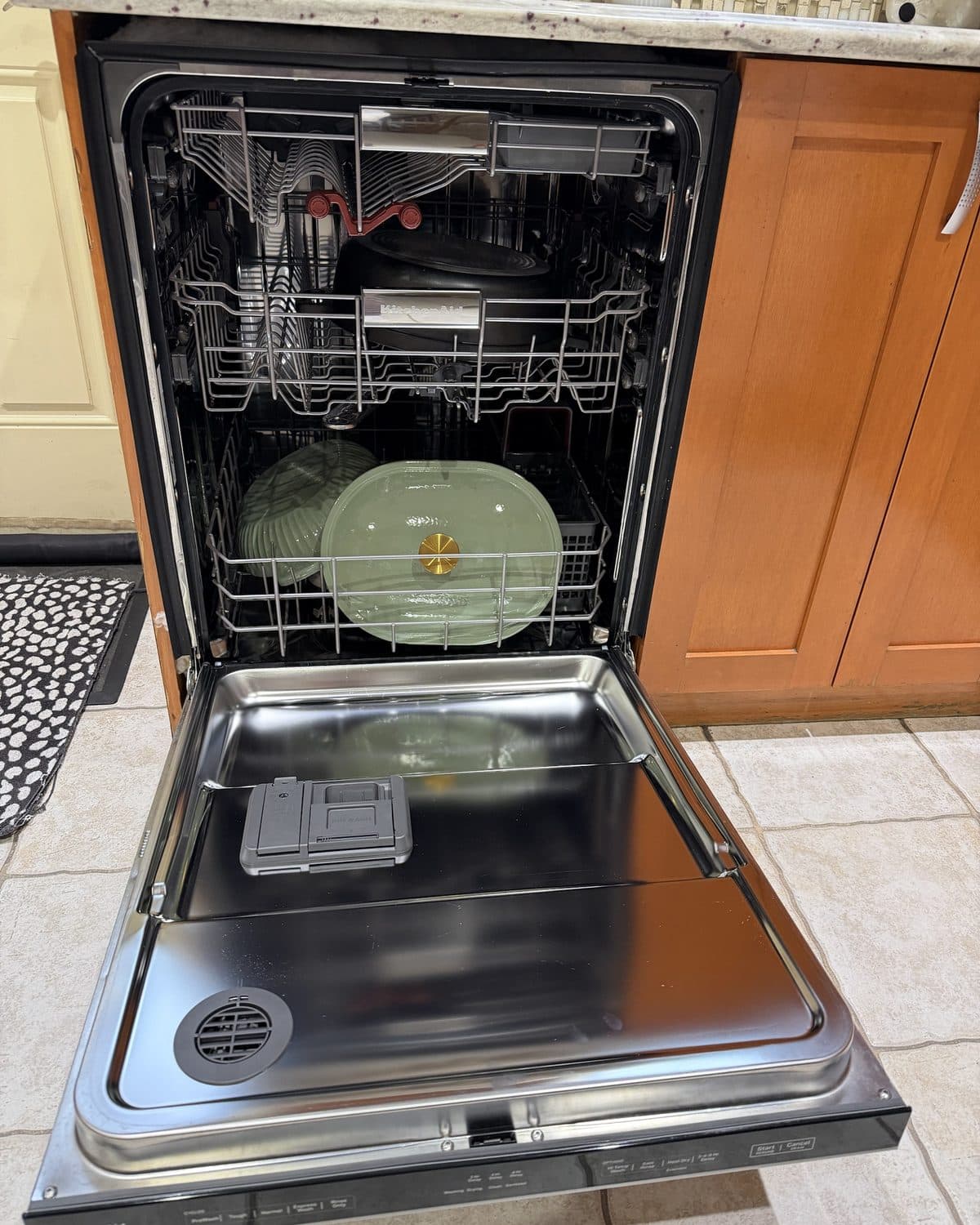 A built-in dishwasher fully open in a Brooklyn kitchen — both racks, the door, and the detergent dispenser exposed for cleaning