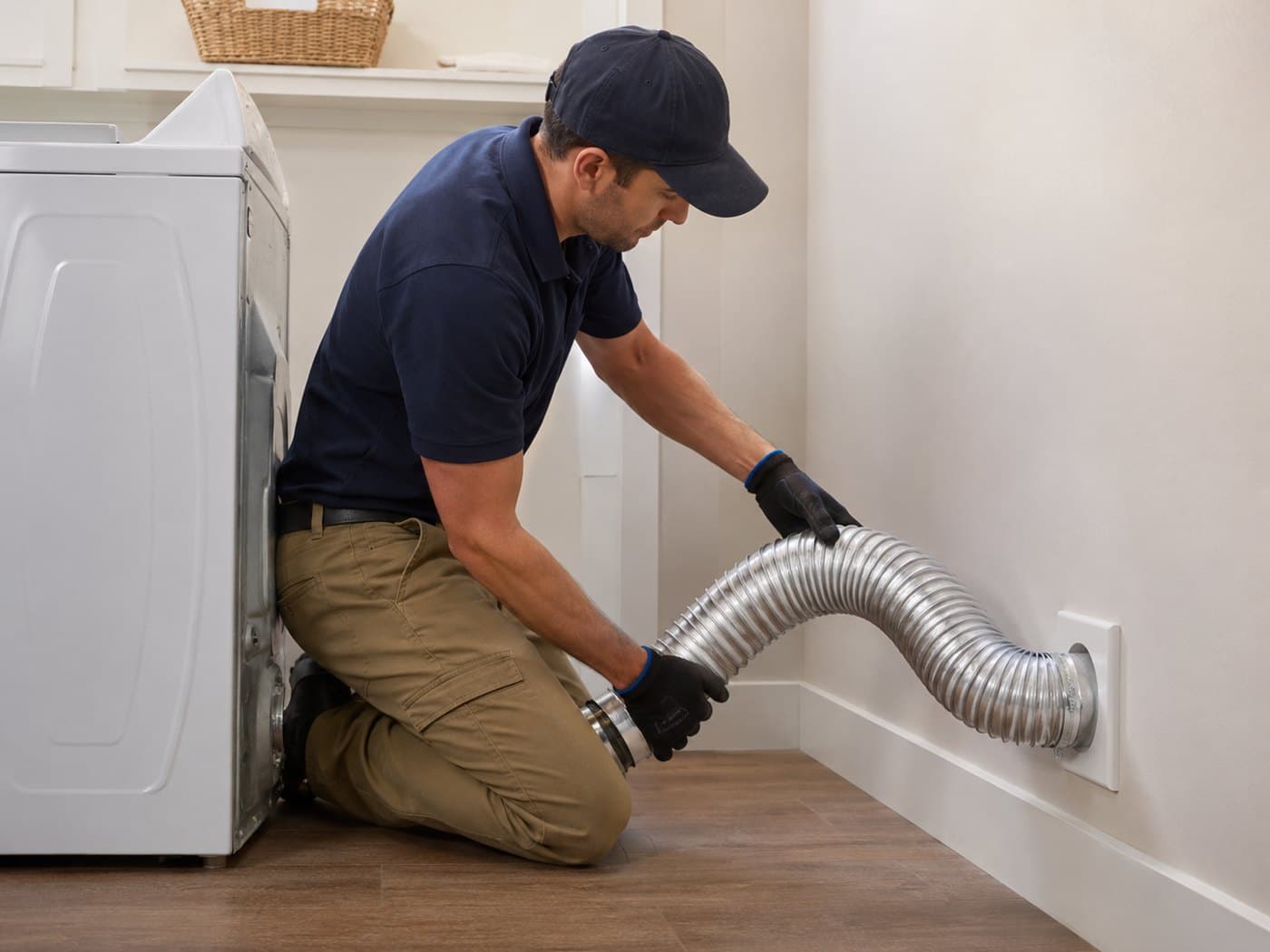 Vent Pro NYC technician connecting a new fireproof metal transition hose from a dryer to the wall vent inlet