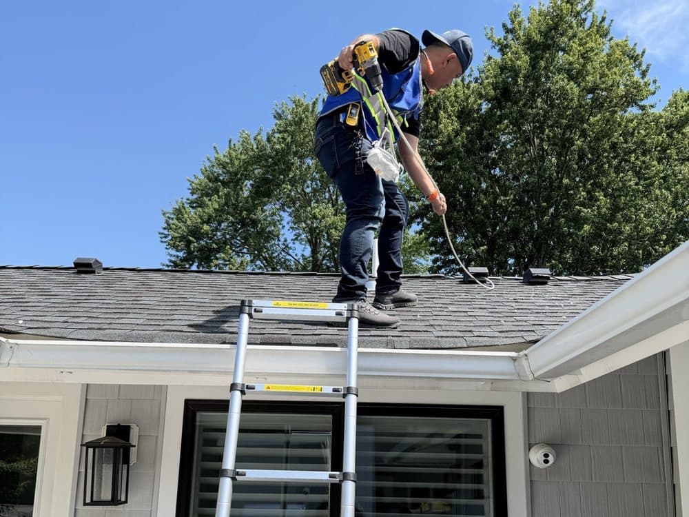 Vent Pro NYC technician on the roof of a home using a drill-driven brush to clear a dryer roof vent