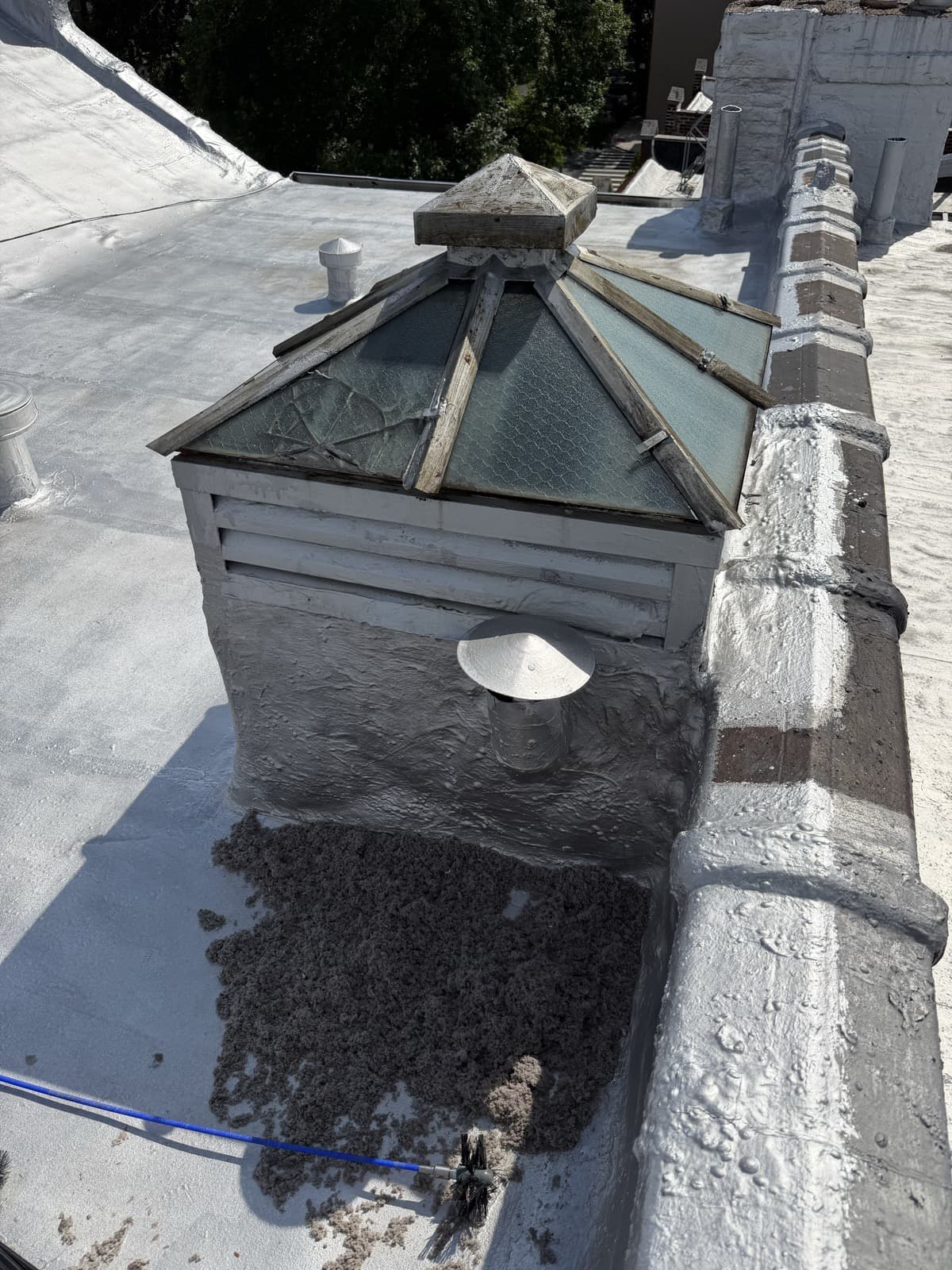 The rooftop of a Brooklyn brownstone with a skylight and a roof dryer vent, cleared lint spread beside the vent