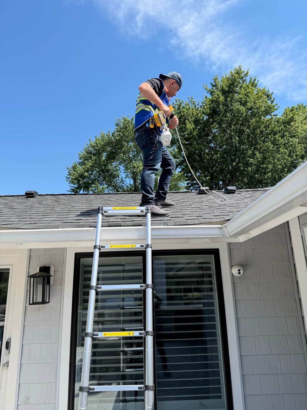 A Vent Pro NYC technician standing on a New Jersey rooftop, feeding a rotary brush rod down into a roof dryer vent line